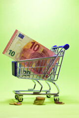 Euro coins and banknotes, green background, copy space. Vertical, close-up shot.