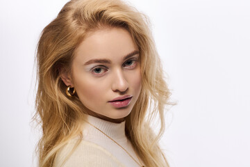Naklejka premium Elegant young blonde in a cozy knitted outfit on a white backdrop