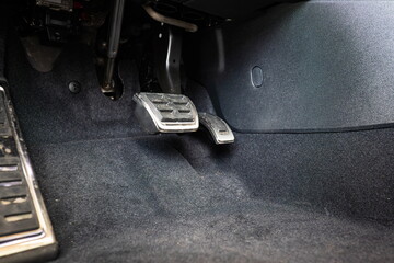 New car gas and break pedals inside driver footwell. Wide angle, close up shot, no people