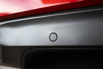 New car fender or bumper mounted, round parking sensor. Close up, detail shot, no people