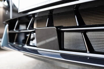 New car fender mounted ADAS or ACC radar cruise control unit. Close up shot, ground level, no people