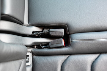 New car rear seats belt buckles neatly stored in bench indentation. Top down, close up shot, no people