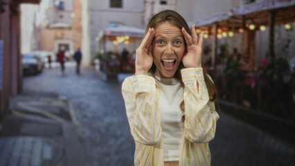 Young hispanic woman covering her face with hands on a bustling restaurant terrace along a...