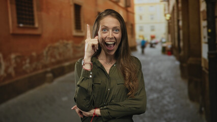 Fototapeta premium Woman points finger up on a cobblestone street with crossed arms and visible necklace; inspiration curiosity.