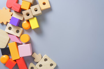 Obraz premium Colorful wooden toy blocks in various shapes on gray background, concept for childhood learning, creativity, education, Montessori play, and preschool development.