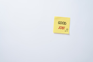 Yellow sticky note with text Good Job and smiley faces on white background, concept for motivation, appreciation, positive feedback, success, and encouragement at work or school.