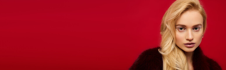 Fototapeta premium Stylish winter fashion with a blonde woman in a vibrant red fur coat