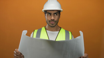 Man engineer wearing hardhat and reflective vest holding blueprint in studio; innovation...