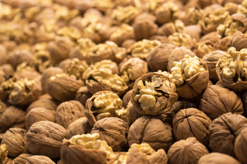 Close view of freshly harvested moist walnuts, cracked shells revealing creamy kernels, shallow depth and warm light; for food design, retail promotion, recipe content, education.