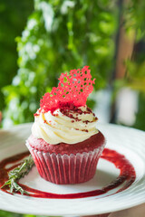 A delightful red velvet cupcake with cream cheese frosting, garnished with a red sugar crisp