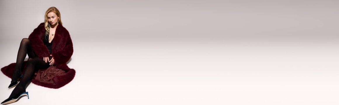 Stylish blonde woman showcasing a bold red fur coat against a winter backdrop