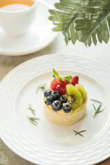 Delicious fruit tart with a cup of tea, beautifully presented. Featuring fresh berries and kiwi on a delicate pastry
