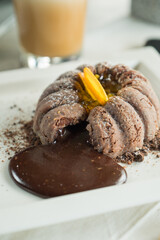 A delectable chocolate lava cake with melted chocolate, served on a white plate. Next to it a glass of beverage