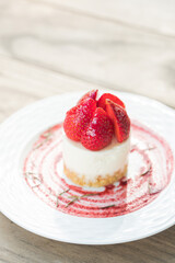 A delicious cheesecake topped with fresh strawberries, elegantly presented on a plate. The cheesecake is creamy, with a buttery crust and juicy strawberries