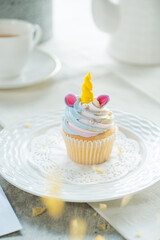 A delightful unicorn cupcake sitting on a decorative plate, a sweet and whimsical treat perfect for any occasion. The cupcake is adorned with colorful frosting and a vibrant unicorn horn