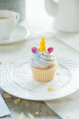 A cute unicorn cupcake on a plate, ready to be enjoyed! This delicious treat features colorful frosting and a whimsical design. 