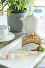 A refined plate presenting a gourmet cake with fresh sides, accompanied by a tea set with a potted plant adding a touch of nature