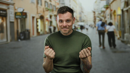 Fototapeta premium Young man with tattooed arm smiling on busy city street wearing casual green shirt urban background
