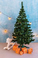 Wooden rocking horse toy in white placed on wooden floor, with decorated Christmas tree and glowing lights and fireplace in background. Concept for childhood, holiday, nostalgia, Christmas decor.