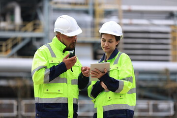 Engineers male, female working with tablet in industry oil refinery oil, gas refinery background, Business petrochemical industrial Ecosystem estates. Fuel refinery industry for transportation.