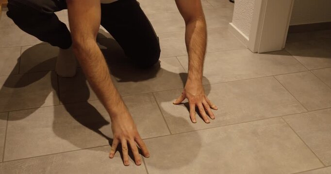 A floor installer kneels and inspects ceramic tiles for defects or unevenness, symbolizing quality control, craftsmanship, and construction safety.