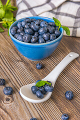 Freshly picked blueberries on an absolute black marble background and a rhodium-plated silver spoon
