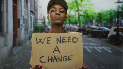African american woman soldier holds cardboard protest sign on city street; social change...