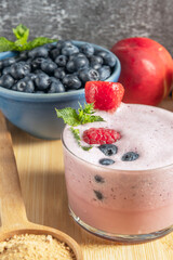 Composition with blueberries and a blueberry and gelatinized maca smoothie on a dark cherry wood table
