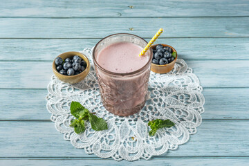 Freshly picked blueberries and a blueberry and almond flour smoothie on an Italian walnut wood table