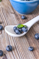 Mountain blueberries on a wet black slate background and a perfectly polished boxwood spoon