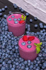 Still life with blueberries and a blueberry and spirulina smoothie on a wooden board