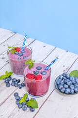 Sustainably farmed blueberries and a blueberry and turmeric smoothie on a natural fir wood table