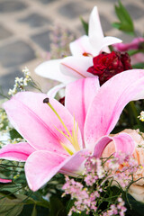pink lily among roses and greens, details of florist crafting gift bouquet with lilies
