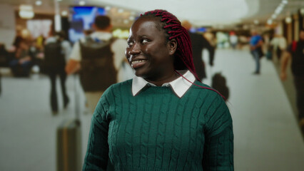 Fototapeta premium Woman smiling in busy airport terminal, indoor setting creates bustling atmosphere, casual attire suggests travel comfort, diverse crowd in background enhances travel theme.