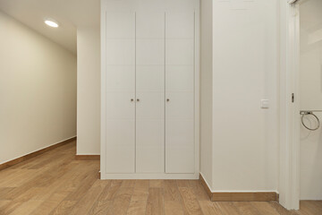 Empty   bedroom with a complete white storage solution, including tall cabinets, drawers, and a desk area