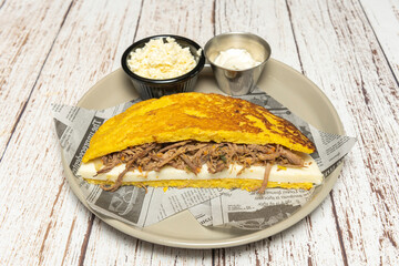 Andean cachapa with melted telita cheese, shredded shredded beef, and sliced ​​avocado, presented on a clay plate