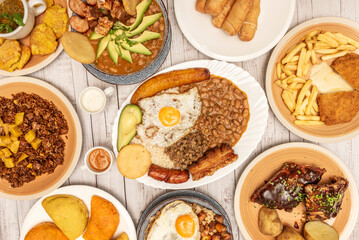 A complete bandeja paisa (tray filled with white rice, red beans, chicharrón, ground beef, plantain, avocado, and arepa, served on a rustic wooden board