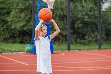 Naklejka premium Focused girl holding basketball on court