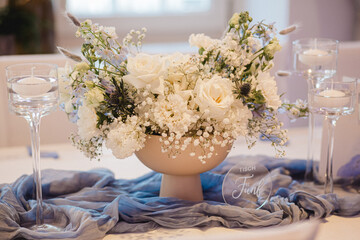 Elegante Hochzeitsdekoration mit weißen Blumen und blaugrauen Stoffen, festlich gedeckter Tisch im...