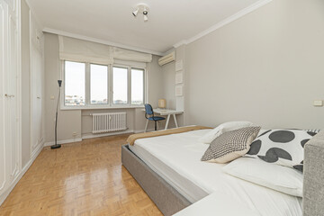 Modern bedroom with a single bed, study table with drawers, and a standing coat rack