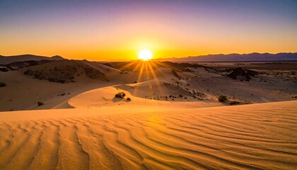 Desert landscape at dusk. The sun radiates light over rolling sand dunes and distant mountains, creating a vibrant orange and blue sky