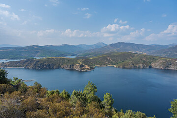 Panoramic view of the Atazar Reservoir on a day of absolute calm, where the water becomes a perfect mirror reflecting cottony clouds