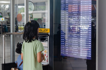 Jakarta, Indonesia - October 19, 2025: Two little Asian girls looking at flight schedule information on the flight schedule board