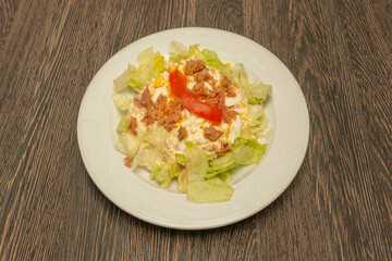 Traditional Russian salad with potatoes, carrots, and cooked peas, mixed with tuna in oil and homemade mayonnaise, garnished with a hard-boiled egg.
