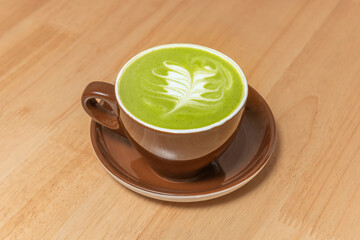 A deep green blended iced matcha drink in a glass cup, elegantly decorated and served against a gray cement background