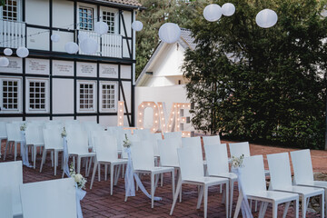 Hochzeitszeremonie im Freien mit Blumenkreis und weißen Stühlen