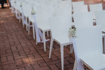 Hochzeitszeremonie im Freien mit Blumenkreis und weißen Stühlen
