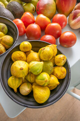 Photo composition where the velvety skin of the figs contrasts with the softness of the pears, avocados, potatoes, and nectarines on a light blue background