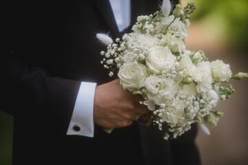 Eleganter Brautstrau&szlig; aus wei&szlig;en Rosen und Schleierkraut in den H&auml;nden des Brautpaars