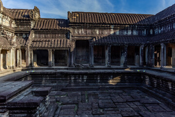 Obraz premium Inner courtyard of the angkor wat temple in siem reap, cambodia, showing a ritual bathing pool, weathered sandstone columns and carved details in morning light